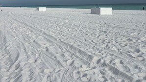 Una spiaggia sabbiosa con solchi di pneumatici e un cielo nuvoloso.