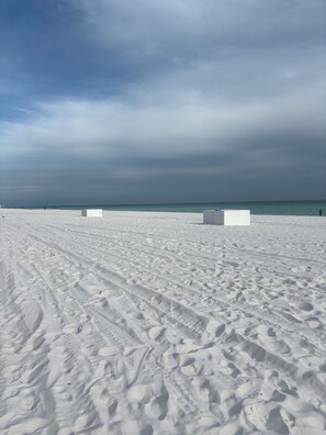 Ein sandiger Strand mit Radspuren und bewölktem Himmel.