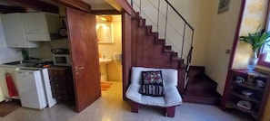 A compact living space with a kitchenette, a dining area, and a staircase leading to an upper level. - Casa Dino room (Roma)