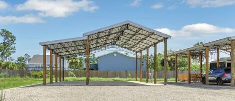A covered outdoor area with a gravel ground, wooden posts, and a metal roof structure.