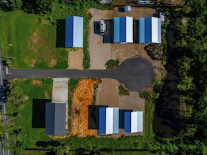An aerial view of a property with multiple buildings, a large open area, and a road.