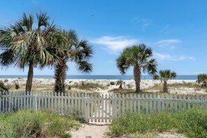 A beach view with a white fence, palm trees, and a clear sky. - Beachfront Home | Hot tub | Pet Friendly | Sea Palms (Indian Pass)