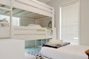 Une chambre avec un lit superposé, une fenêtre et un bureau.