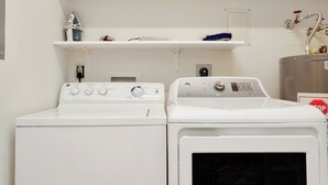 A laundry area with two white washing machines and a metal water heater. - Beachfront Home | Hot tub | Pet Friendly | Sea Palms (Indian Pass)