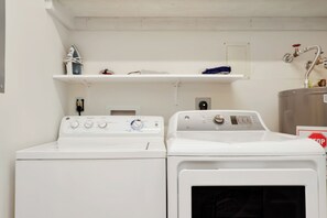 A laundry area with two white washing machines and a metal water heater. - Beachfront Home | Hot tub | Pet Friendly | Sea Palms (Indian Pass)