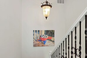 A staircase with a black railing and a wall-mounted picture of a red bucket filled with seashells. - Beachfront Home | Hot tub | Pet Friendly | Sea Palms (Indian Pass)