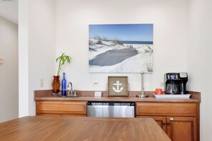 A kitchen with a wooden countertop, a coffee maker, a dishwasher, and a framed picture of a beach scene. - Beachfront Home | Hot tub | Pet Friendly | Sea Palms (Indian Pass)