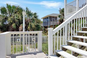 A wooden deck with a white railing, leading to a house with a balcony. - Beachfront Home | Hot tub | Pet Friendly | Sea Palms (Indian Pass)