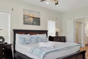 A bedroom with a bed, a nightstand, a lamp, a painting, and a door. - Beachfront Home | Hot tub | Pet Friendly | Sea Palms (Indian Pass)