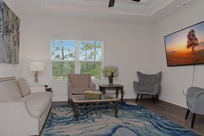 A living room with a sofa, armchairs, a coffee table, and a painting on the wall. - 🌊Seaside Escape | Windmark Beach | Pool + Beach Access (WindMark Beach)