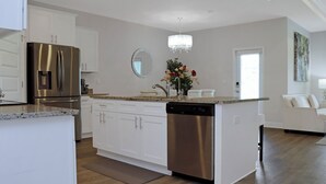 A modern kitchen with white cabinetry, a stainless steel refrigerator, a dishwasher, and a central island with a sink and countertop. - 🌊Seaside Escape | Windmark Beach | Pool + Beach Access (WindMark Beach)