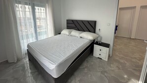 A modern bedroom with a bed, bedside table, and a view of the outside through a window.