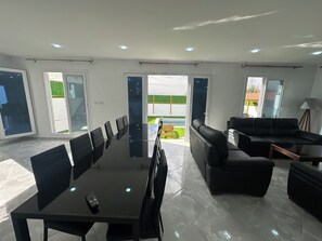 A spacious room with a conference table, black leather sofas, and a large glass door leading outside.