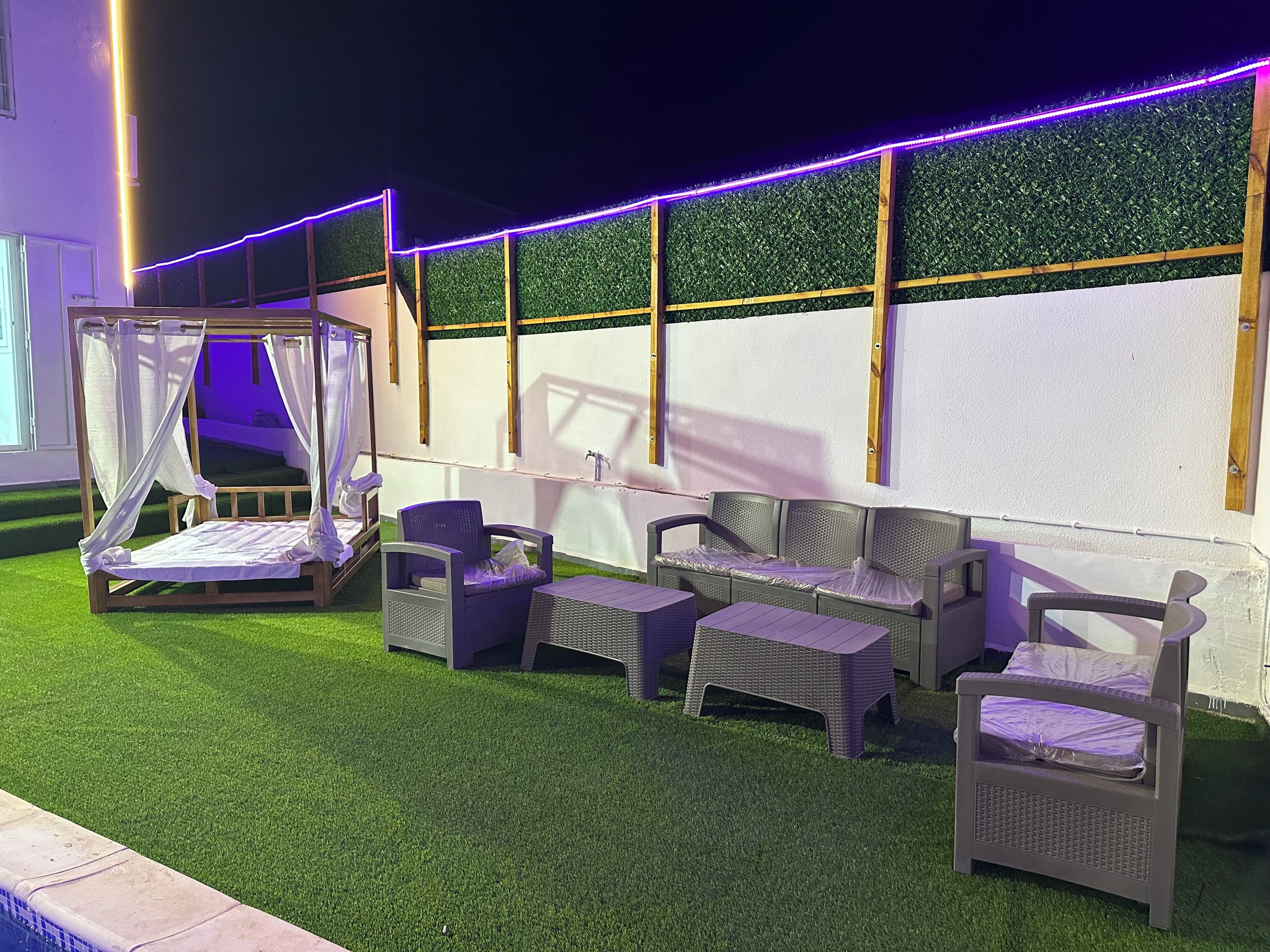 A patio area with a bed, chairs, and a small table.