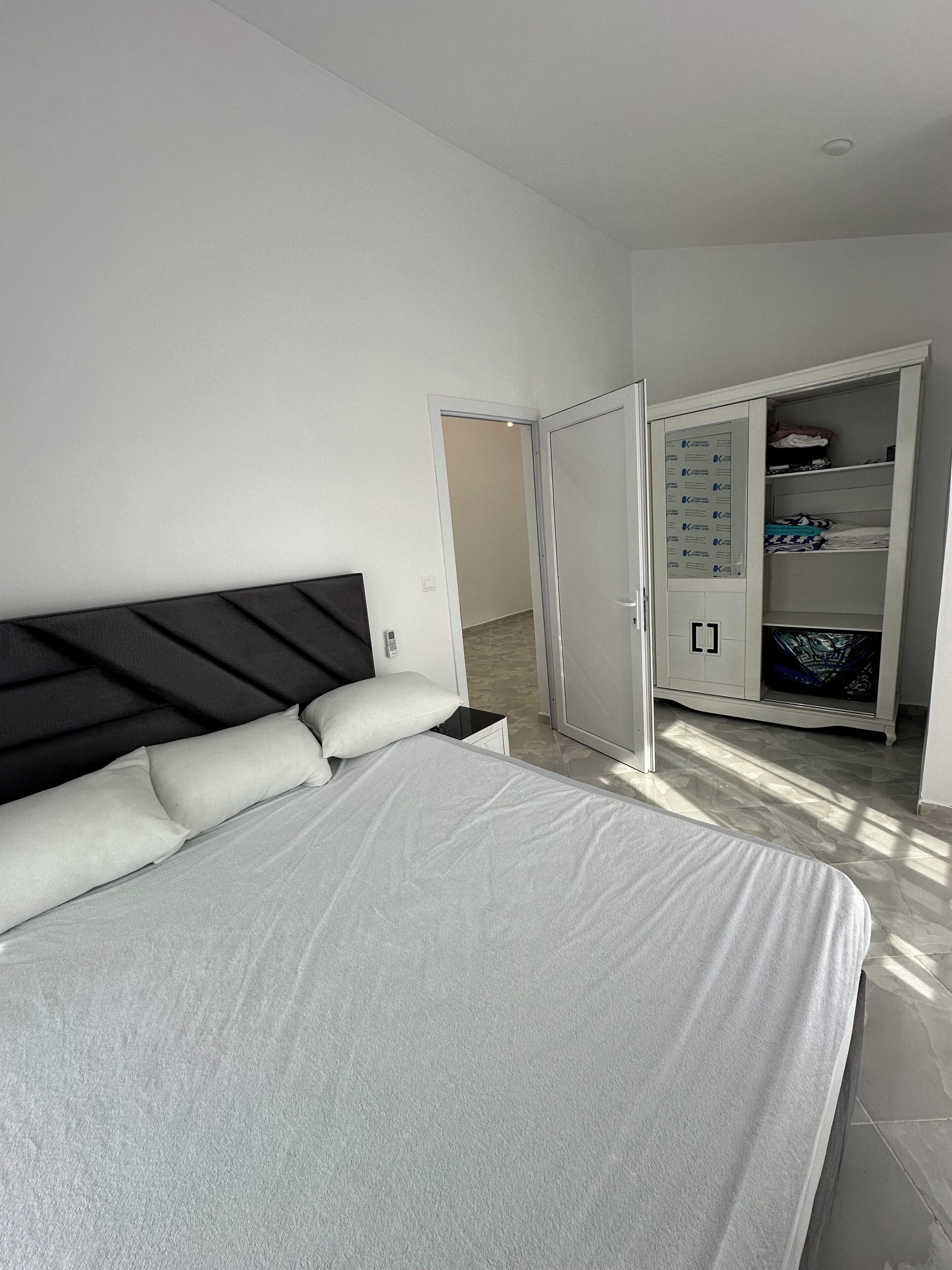 Ein Schlafzimmer mit einem Bett, einem Kleiderschrank und einer Tür zu einem anderen Raum.