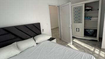 Ein Schlafzimmer mit einem Bett, einem Kleiderschrank und einer Tür zu einem anderen Raum.