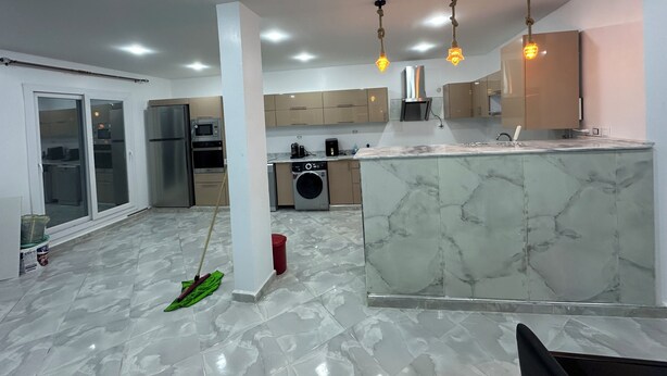 A modern kitchen with a marble island, built-in appliances, and pendant lighting.