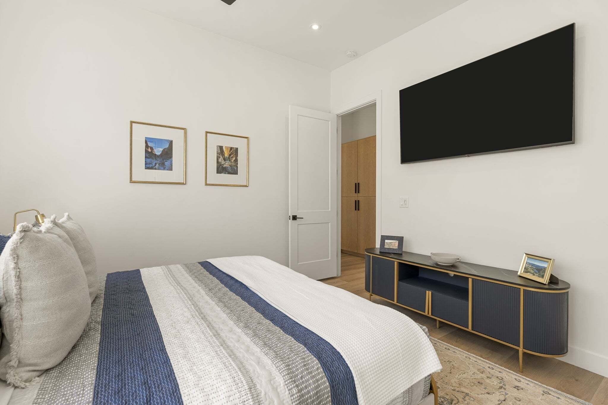 A bedroom with a bed, a dresser, a television, and two framed pictures on the wall.