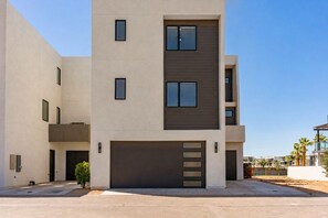 A modern multi-story residential building with a garage, multiple windows, and a flat roof. - Lagoon Landing 7 Bedroom Home (St. George)