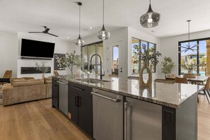 A modern kitchen with a central island, stainless steel appliances, and pendant lighting. - Lagoon Landing 7 Bedroom Home (St. George)