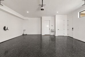 A spacious, empty room with a polished floor, white walls, and a ceiling-mounted projector. - Lagoon Landing 7 Bedroom Home (St. George)