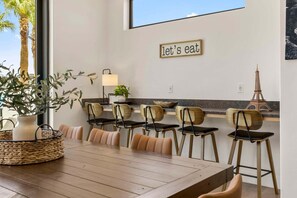 A dining area with a wooden table, six chairs, a lamp, and a sign that reads 'let's eat'. - Lagoon Landing 7 Bedroom Home (St. George)