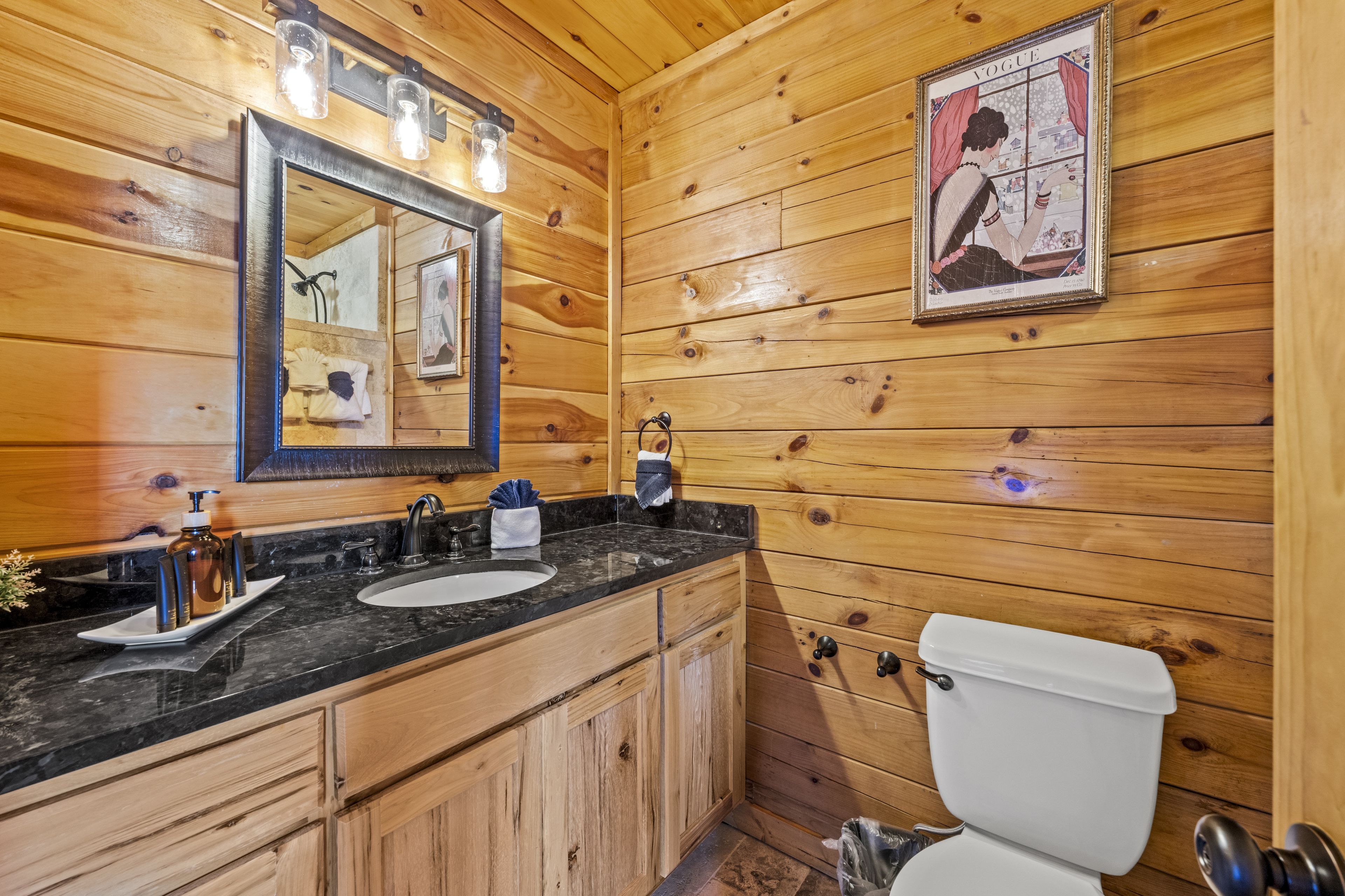 Baño de cabaña de madera con lavabo, espejo e inodoro.