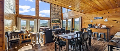 A cabin interior with a dining area, seating, and a fireplace.