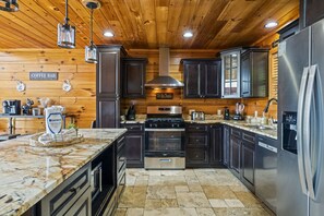 Een moderne keuken met houten lambrisering, roestvrijstalen apparatuur en een marmeren aanrecht.