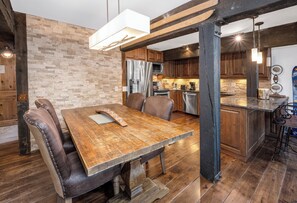 Eine rustikale Küche mit Holdekor, einem Edelstahlkühlschrank und einer Bar mit Barhocker.