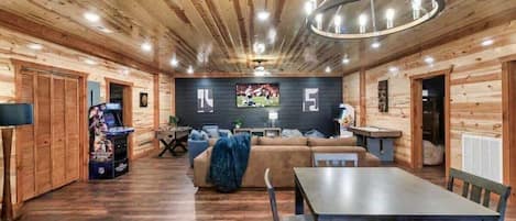 A log cabin interior with a dining area, sofa, and television.