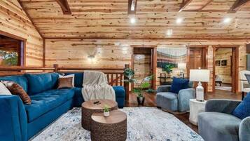 A log cabin interior with a blue sofa, grey armchairs, and a round coffee table.