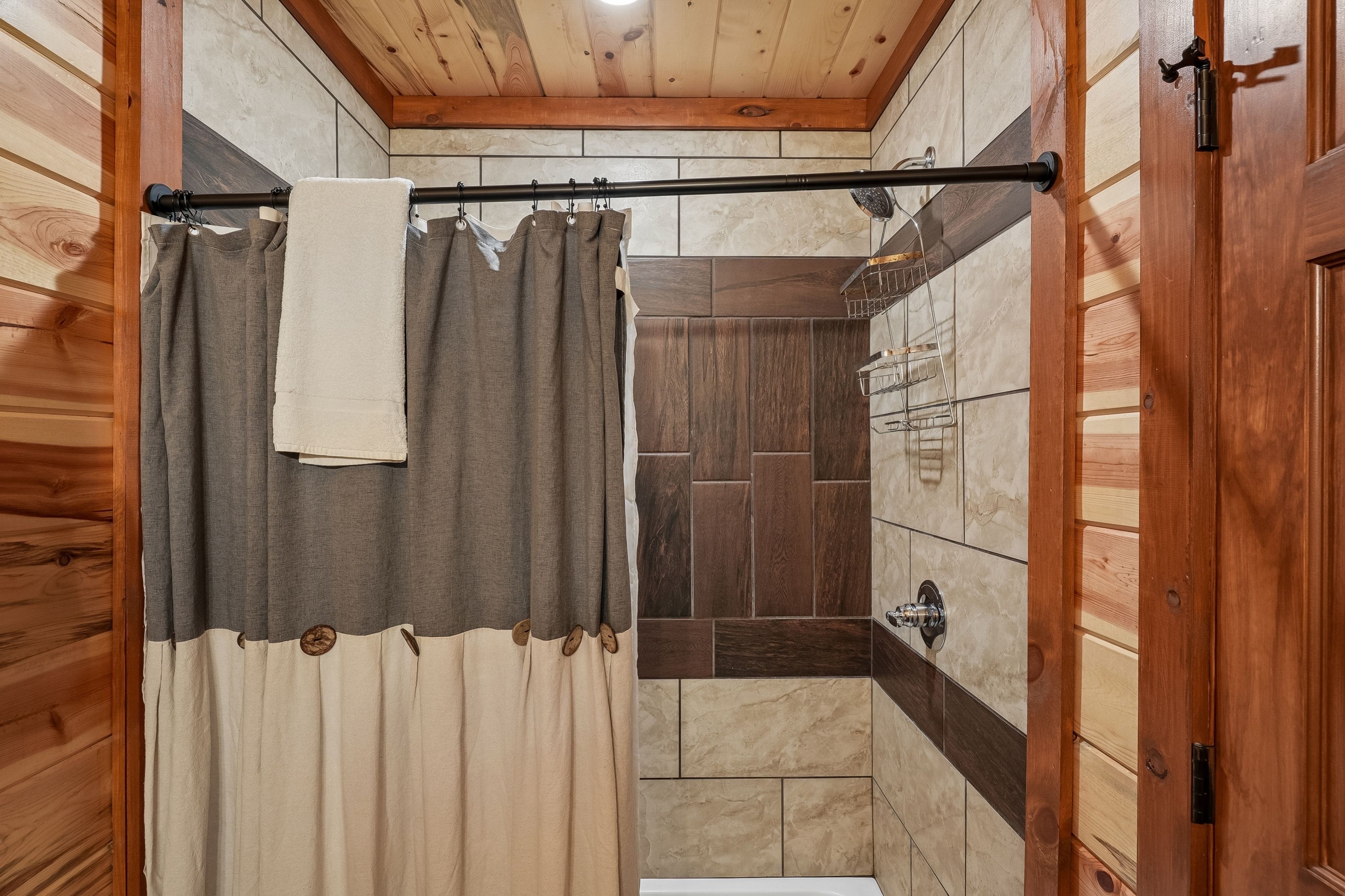 A wooden-paneled bathroom with a shower curtain, a towel hanging on a rod, and a bathtub.