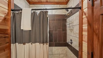 A wooden-paneled bathroom with a shower curtain, a towel hanging on a rod, and a bathtub.