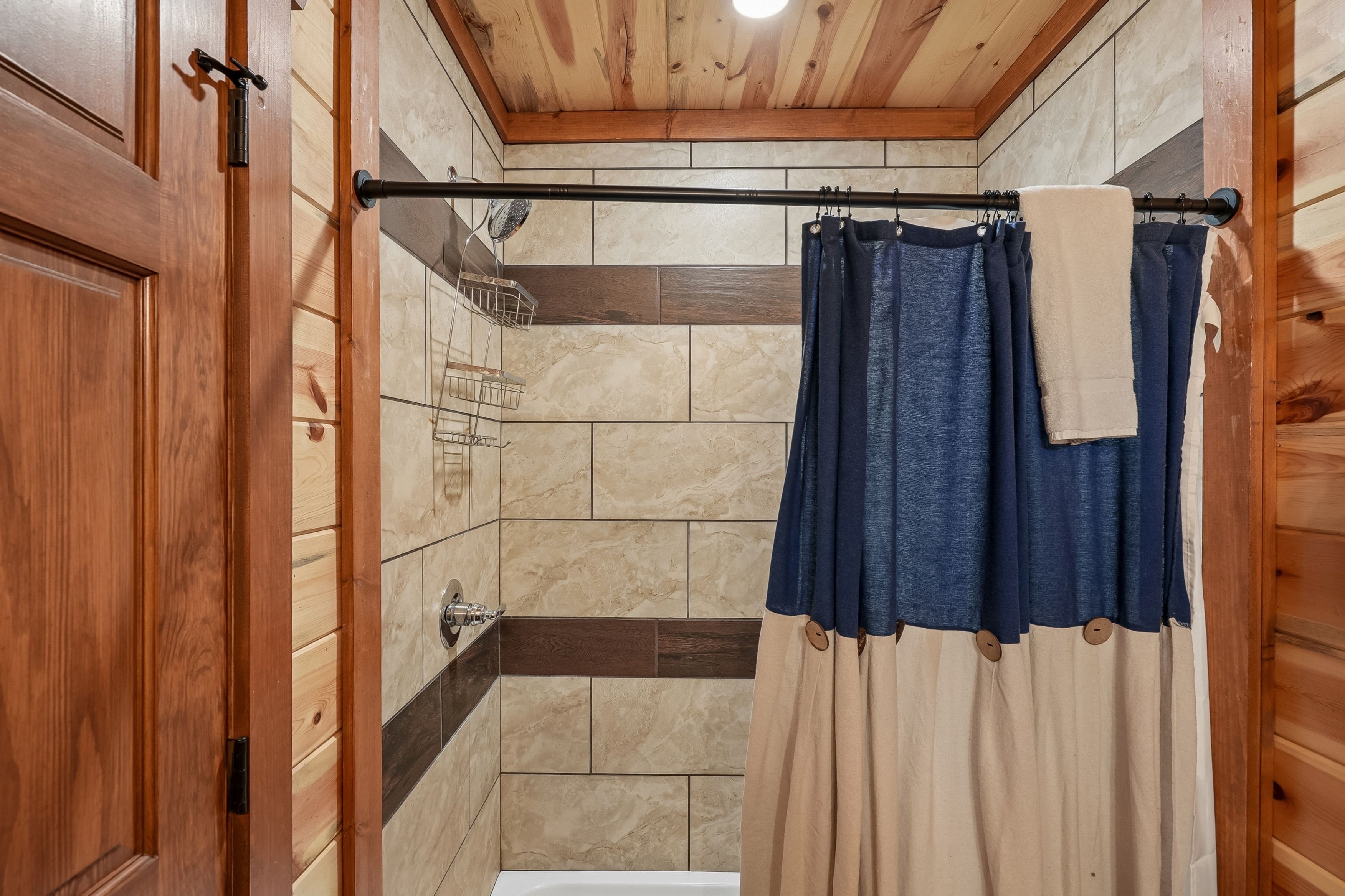A wooden-paneled bathroom with a bathtub, a shower, and a towel rack.