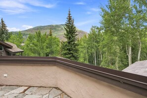 A residential property with a sloped roof, a stone foundation, and a view of a forested mountain range. - For486 5 Bedroom Home (Vail)