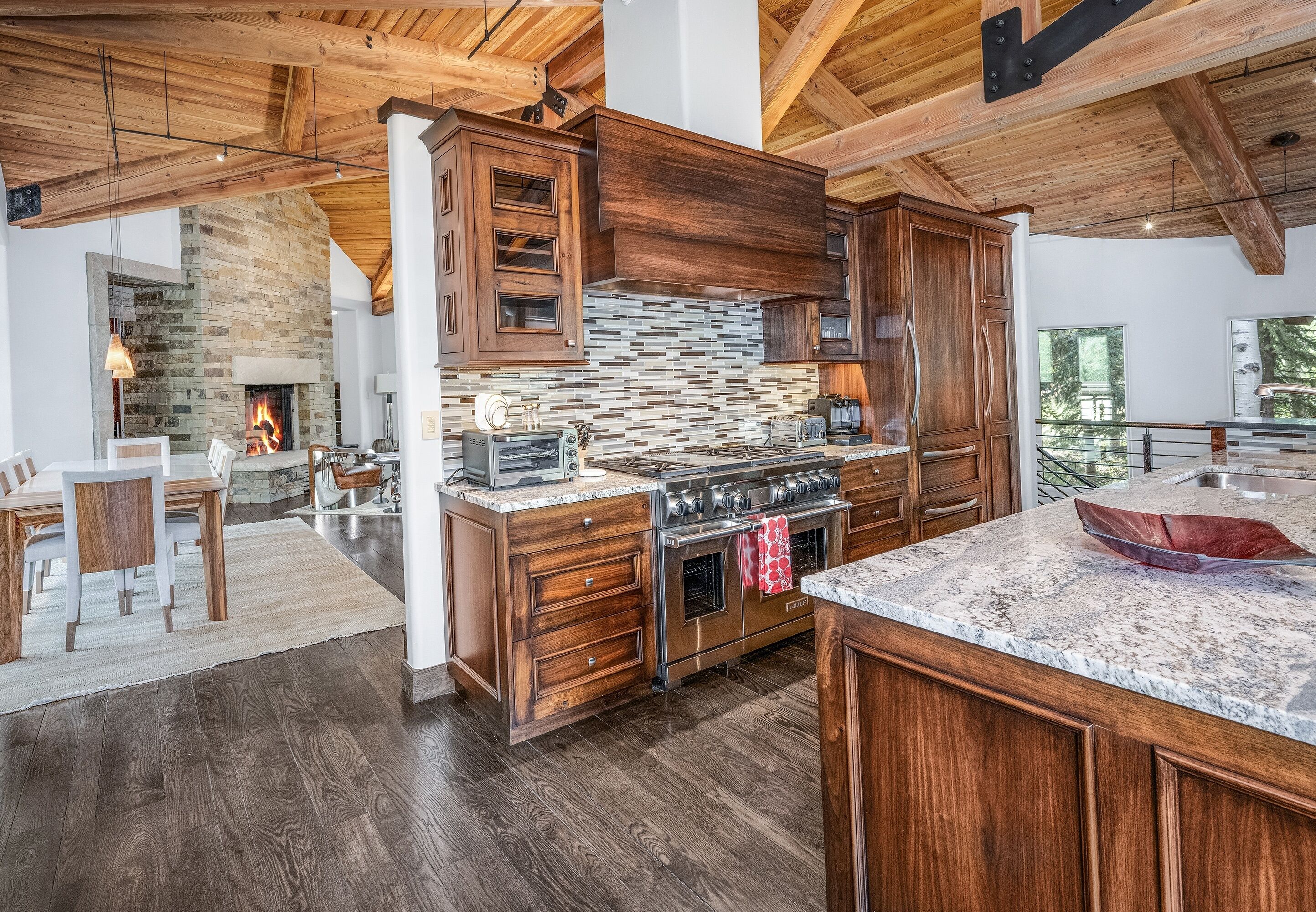 Une cuisine spacieuse dotée de meubles en bois, d’une cheminée en pierre et d’un grand îlot central avec un four encastré.
