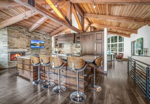 A spacious kitchen with a high ceiling, a stone wall, and a large window. - For486 5 Bedroom Home (Vail)