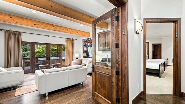 A spacious living area with a white sofa, wooden flooring, and a large wooden door leading to another room. - For486 5 Bedroom Home (Vail)