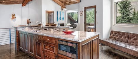 A spacious kitchen with a large island, wooden cabinets, and a built-in dishwasher.