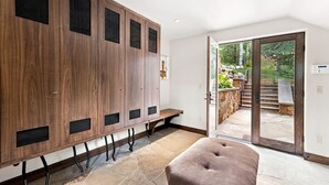 A modern interior with a wooden locker area, a bench, and a glass door leading to an outdoor garden. - For486 5 Bedroom Home (Vail)