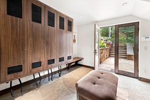 A modern interior with a wooden locker area, a bench, and a glass door leading to an outdoor garden. - For486 5 Bedroom Home (Vail)