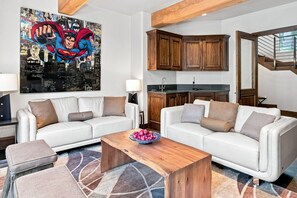 A living room with a white sofa set, a coffee table, and a cityscape painting on the wall. - For486 5 Bedroom Home (Vail)