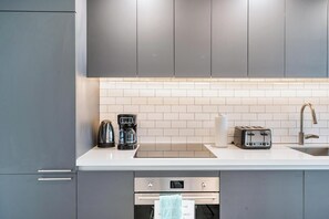 A modern kitchen with grey cabinets, a white countertop, a coffee maker, a toaster, and a sink. - 17th floor skyline retreat in Downtown Miami rooftop pool, coworking lounge and self check-in (Miami)