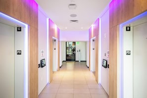 Ein moderner Hotelgang mit beleuchteten Schildern für Zimmer A, B, C, D und E sowie einer digitalen Anzeige mit Zimmerinformationen.