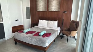 A hotel room with a bed, a chair, a bedside table, and a wardrobe. - Skyline Studio w/ Pool & Gym | Walk to Bayside (Miami)