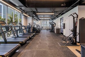A gym with treadmills, exercise equipment, and a view of tall buildings. - Skyline Studio w/ Pool & Gym | Walk to Bayside (Miami)