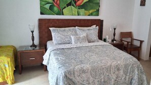 Een slaapkamer met een groot bed, twee nachtkastjes, een stoel en een schilderij aan de muur.