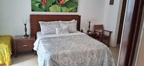 A bedroom with a large bed, two bedside tables, a chair, and a painting on the wall. - P. H. PRIVATE PATIO W/ THERMO TUB./POOL, 1 BLK TO RESTRNT & MRKT, CLOSE TO BEACH (Playa del Carmen)