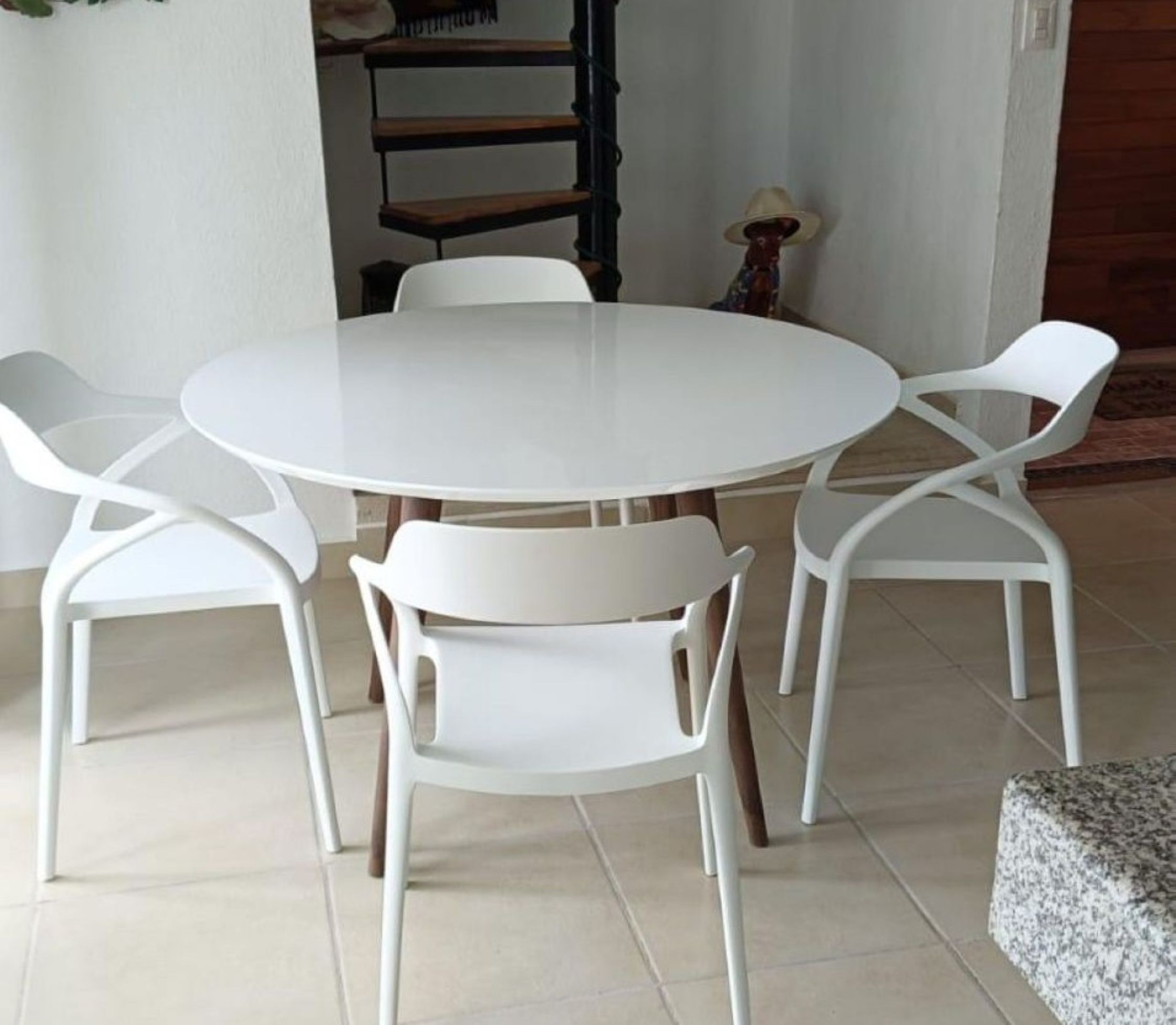 Une table de salle à manger ronde, accompagnée de quatre chaises blanches.